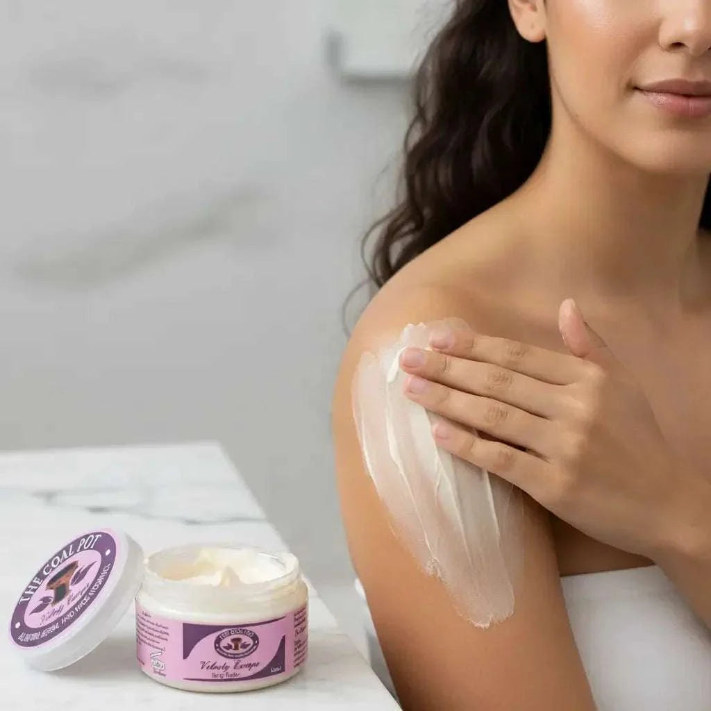 Body Cream/Coal Pot white moisturizer in a pink and purple-labeled jar beside a woman applying cream to her shoulder