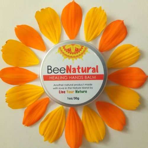 Bee Natural Body Balm in a round metal tin with a white Healing Hands Balm label, surrounded by orange and yellow petals